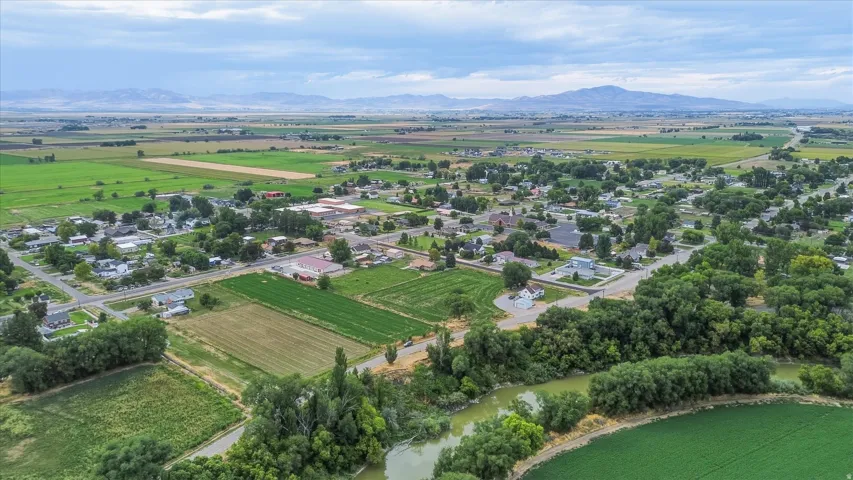 Expansive green fields, a winding river, and distant mountains