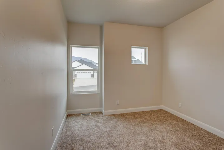 Neutral wall finish, carpeted flooring, large window, and secondary square window