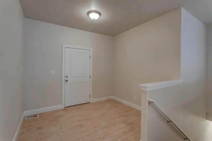 Wood-finish flooring with neutral wall tones and a flush-mount ceiling light