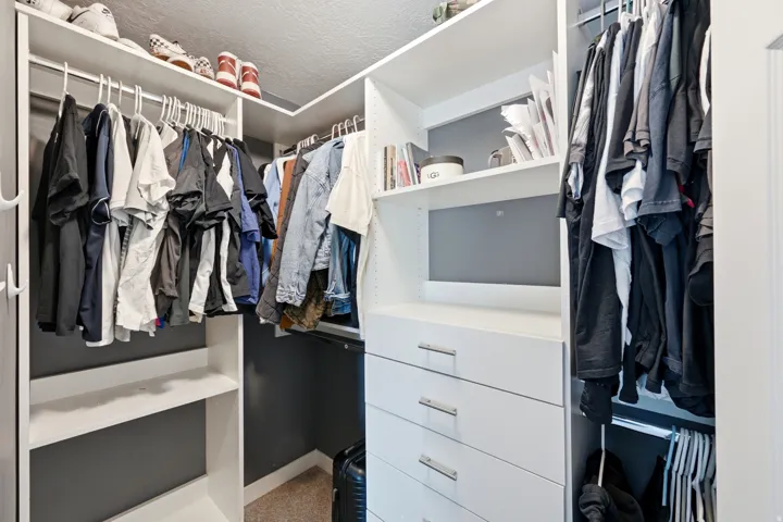 Built-in white custom closet system with multiple shelving units, hanging rods, and integrated drawers with polished hardware