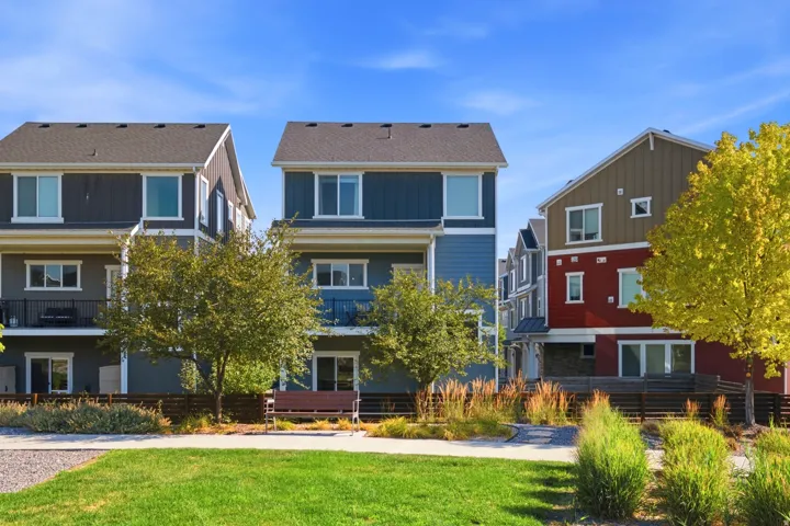 Modern townhome architecture featuring multi-level facades, private balconies, and a vibrant green space