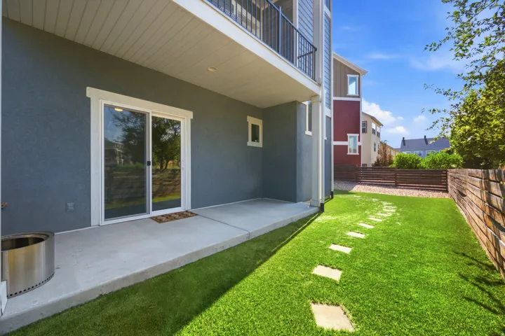 Private patio with a sliding glass door, a manicured lawn, stone pavers, and a horizontal slatted fence