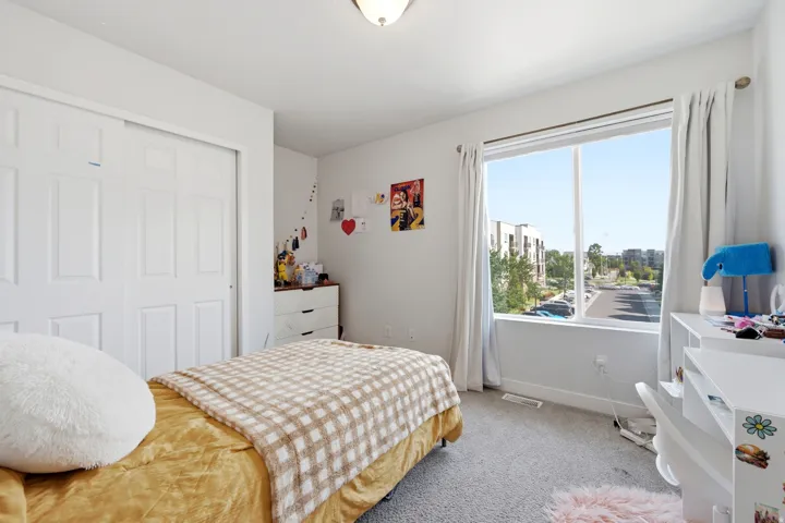 Spacious room featuring carpeting, a built-in closet with bifold doors, and a large window