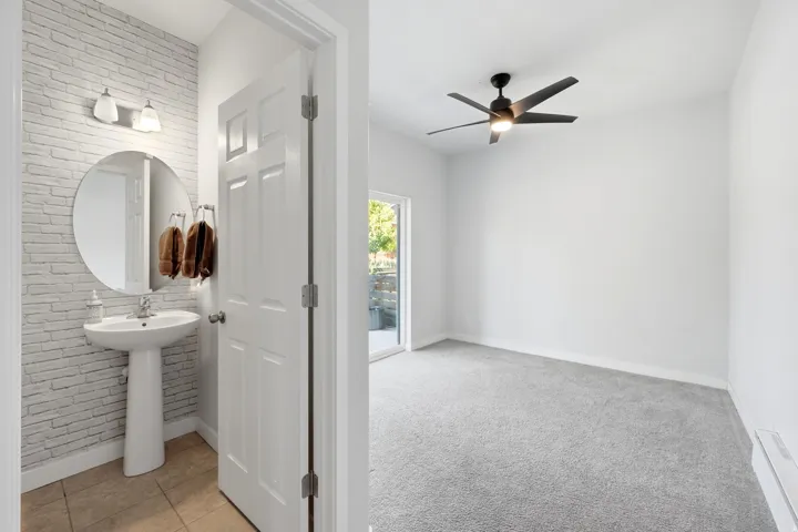 Pedestal sink with a circular mirror and wall-mounted lighting