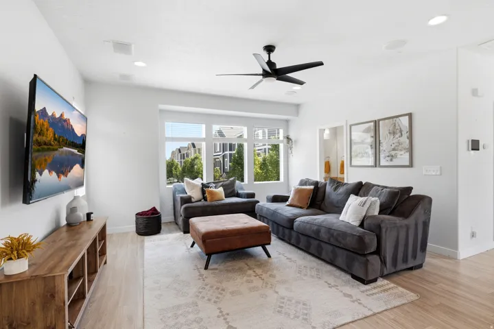 Spacious living area featuring light-toned wood-finish flooring, recessed lighting, and a ceiling fan