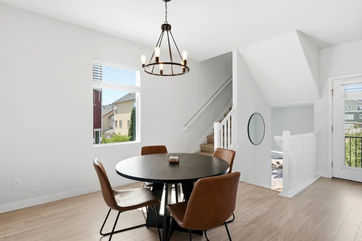 Bright interior featuring wood-finish flooring, a contemporary chandelier, and a large window with horizontal blinds