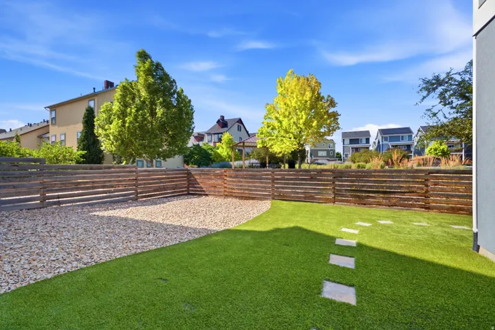 Landscaped yard featuring artificial turf, gravel hardscaping, and a horizontal slatted privacy fence