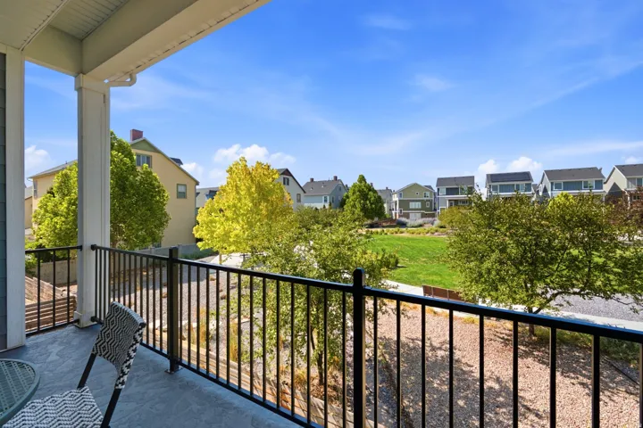 Spacious balcony with black metal railings, a textured concrete surface, and a recessed ceiling