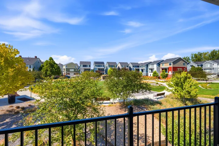 Community park with paved walking paths, mature trees, and a distant residential street