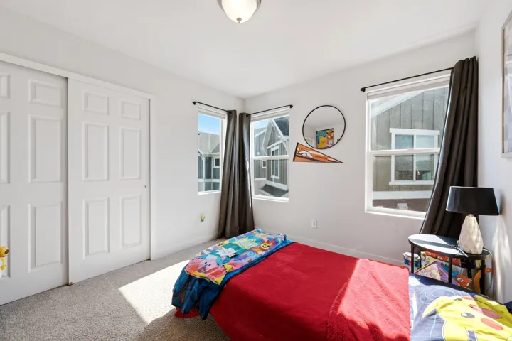 Recessed ceiling light, white walls, carpeted flooring, multiple windows, and a sliding panel door closet
