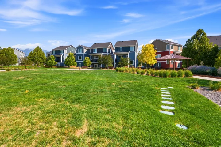 Expansive green space with stepping stone path, surrounding landscaping, and distant mountain backdrop
