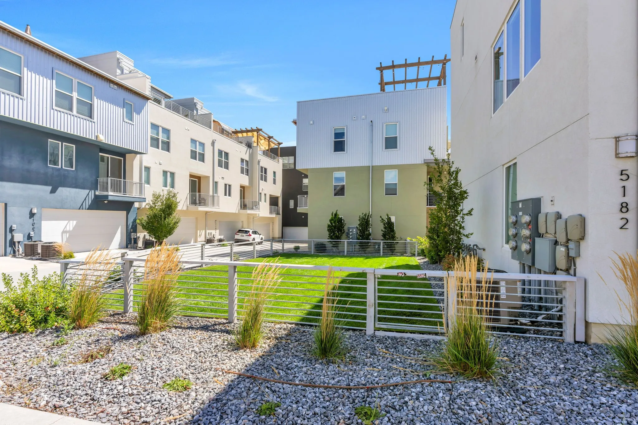 Landscaped common area with a manicured lawn, gravel ground cover, and low fencing