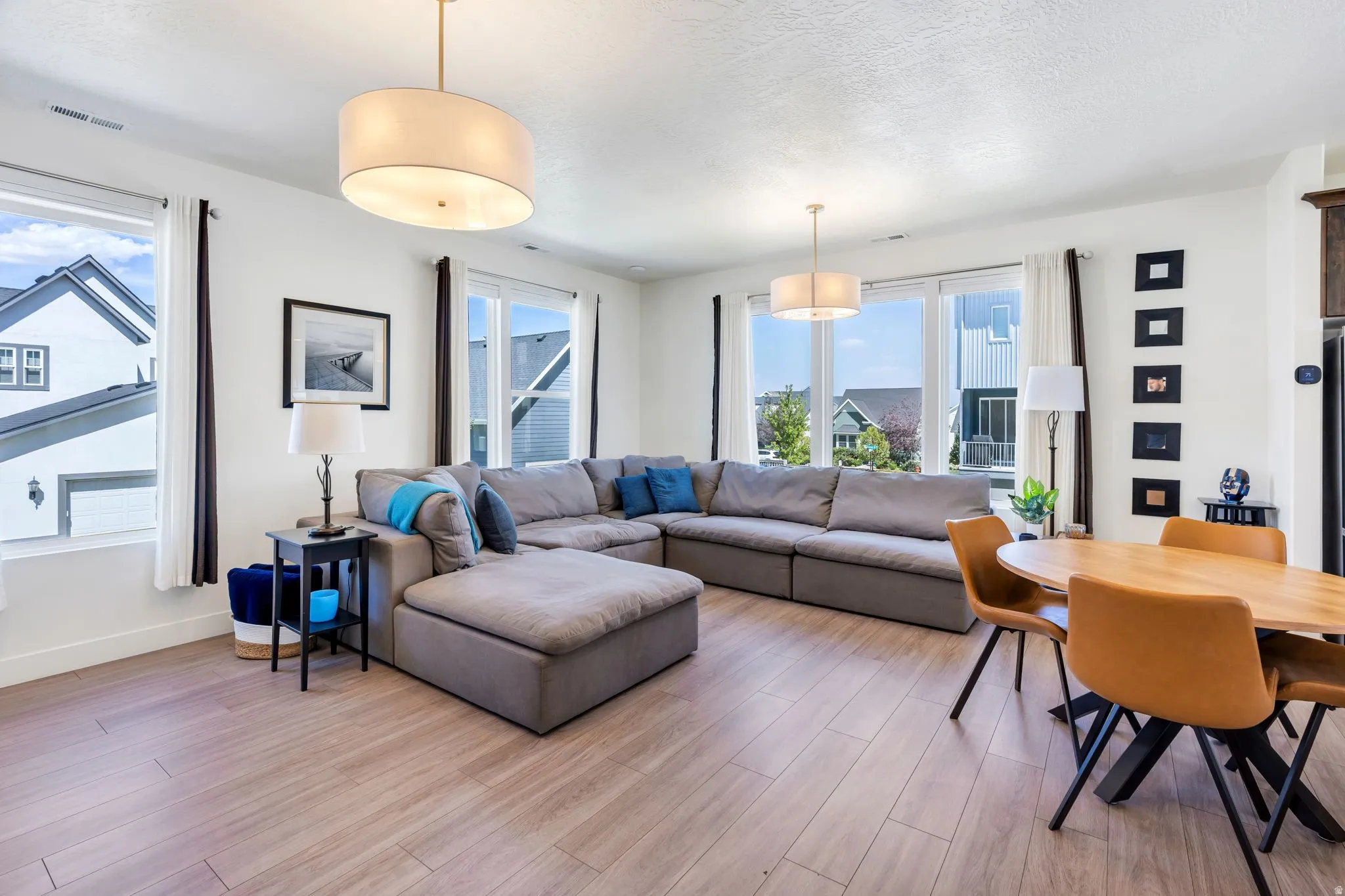 Open-concept living area featuring light wood-finish flooring, recessed lighting, and large windows