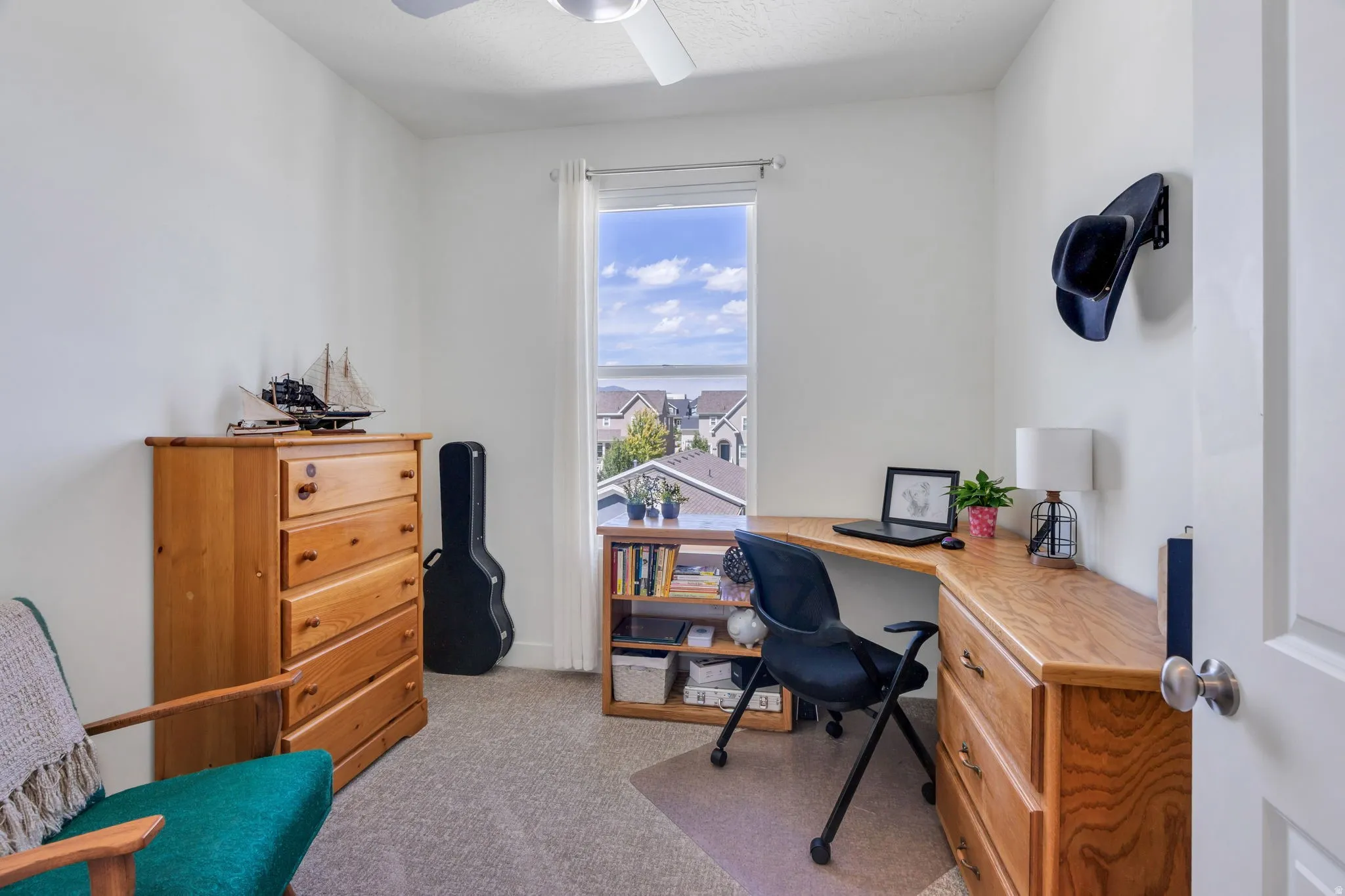 Neutral wall color, ceiling fan, natural light from a single window, and carpeted flooring