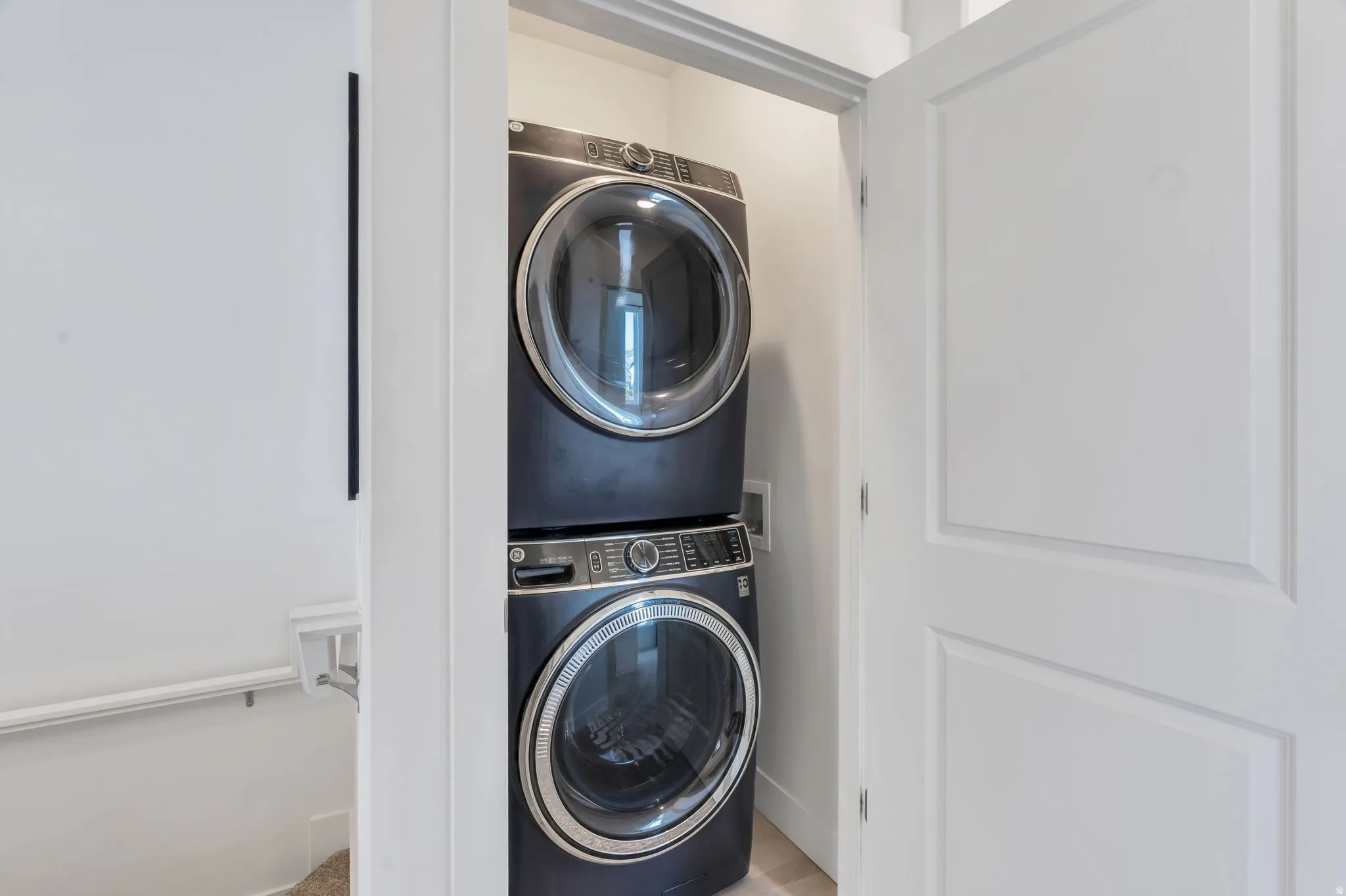 Laundry closet featuring stacked front-load washer and dryer units