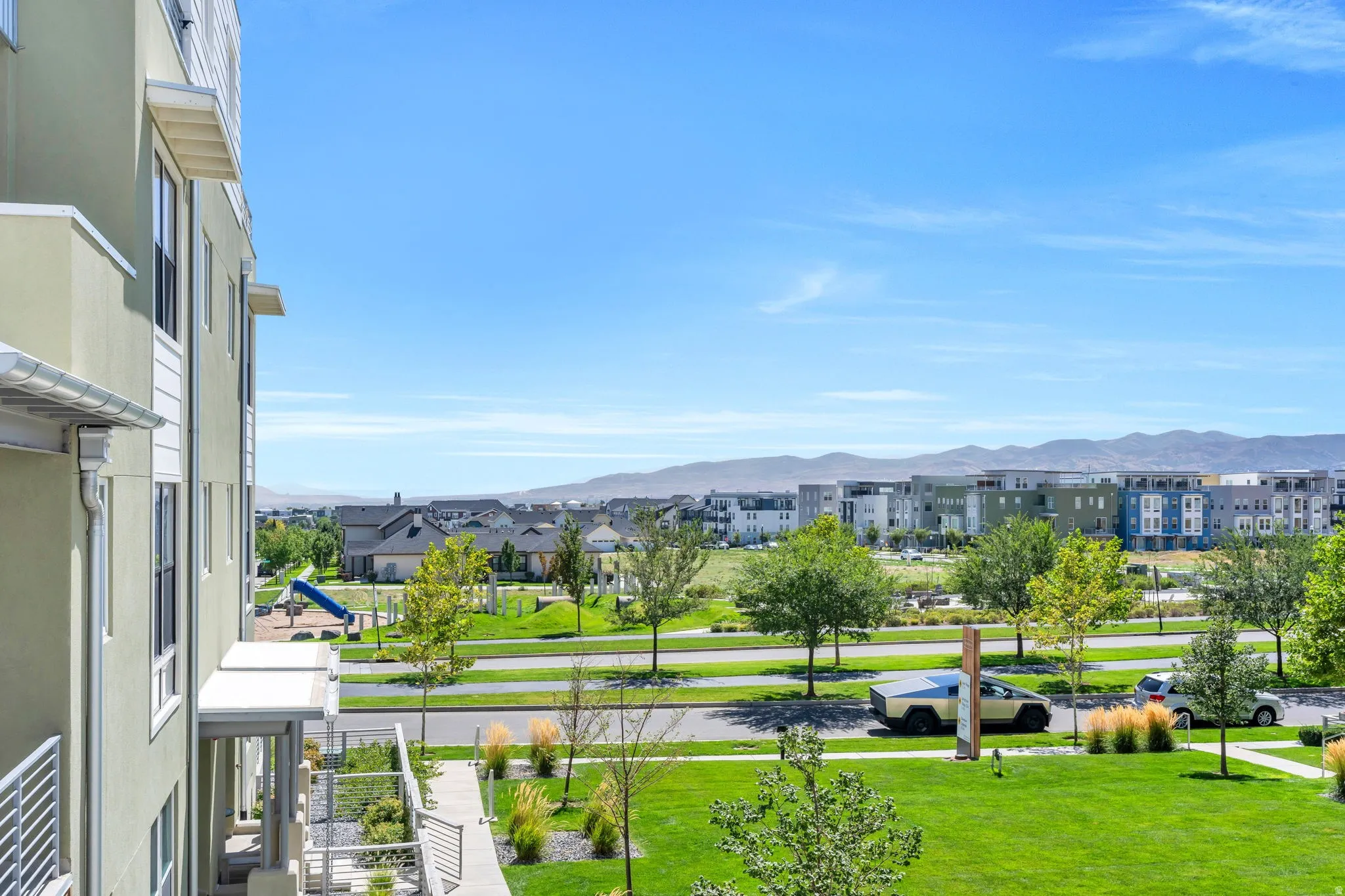 Green spaces and a playground feature prominently in the community setting, with mountains in the background