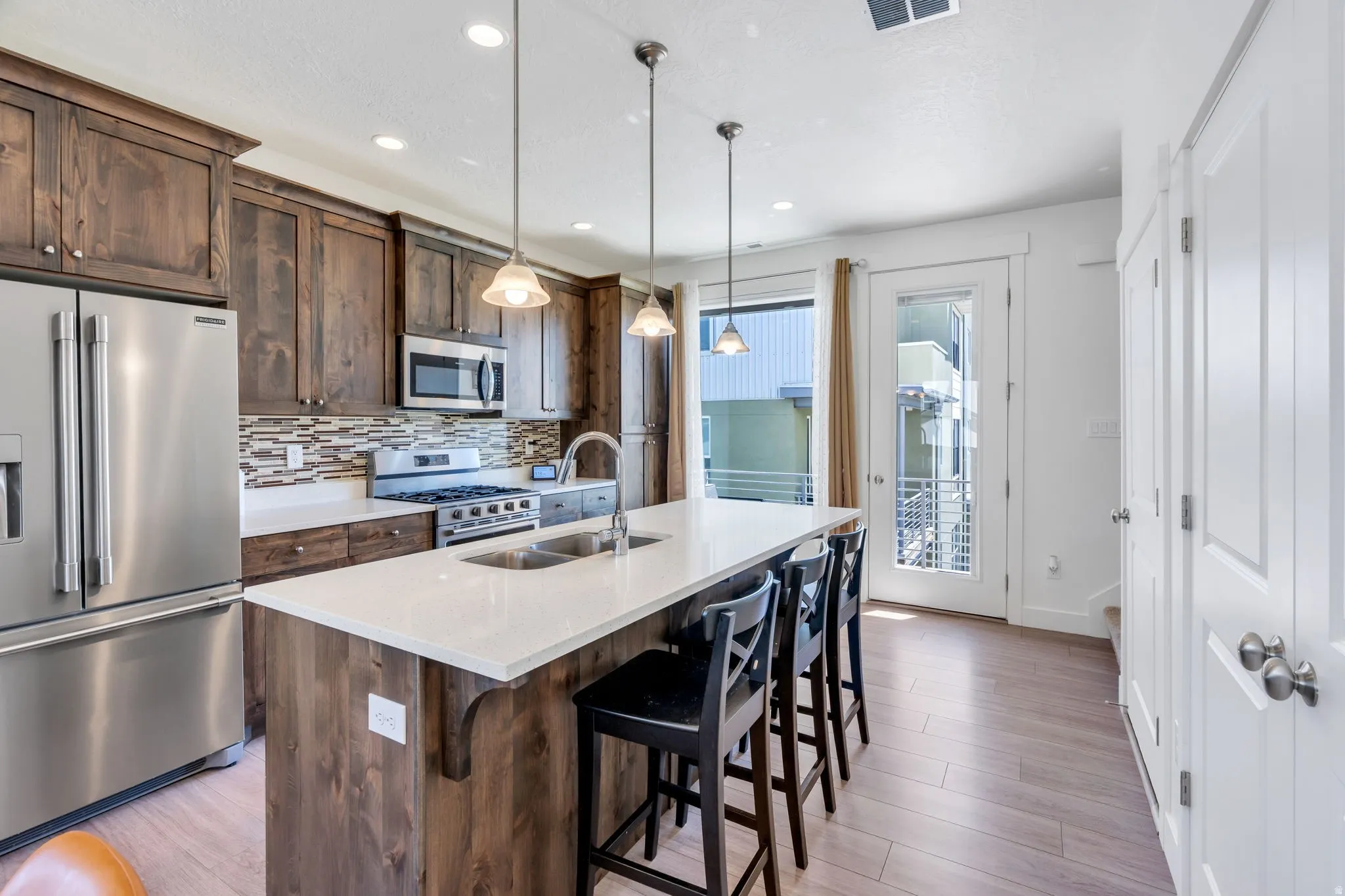 Gourmet kitchen featuring stainless steel appliances, wood-finish cabinetry, a large center island with seating, and wood-finish flooring