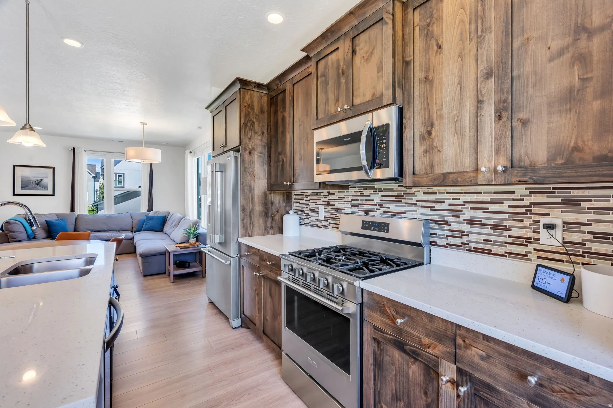 Kitchen featuring wood cabinetry, stainless steel appliances, a multi-tone tile backsplash, and light-tone countertops
