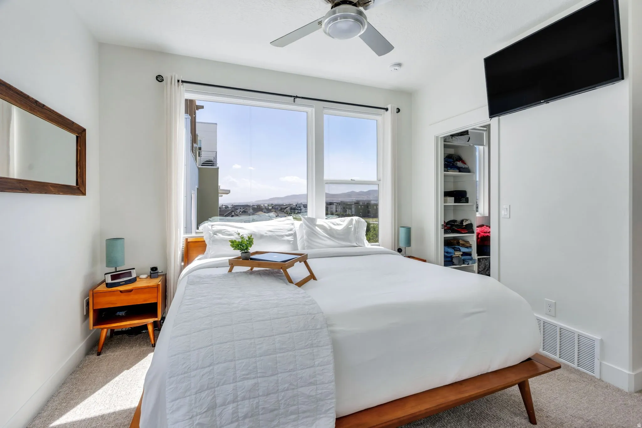 Bright bedroom featuring a large window, ceiling fan, and built-in closet organization system