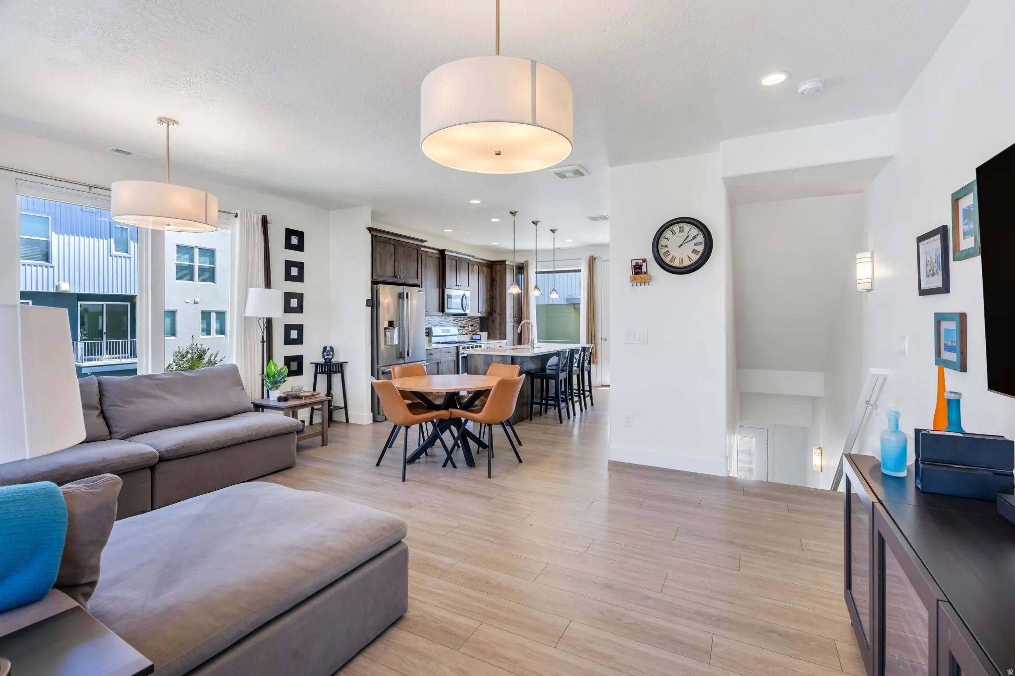 Open-concept living area with wood-finish flooring, recessed lighting, and large windows