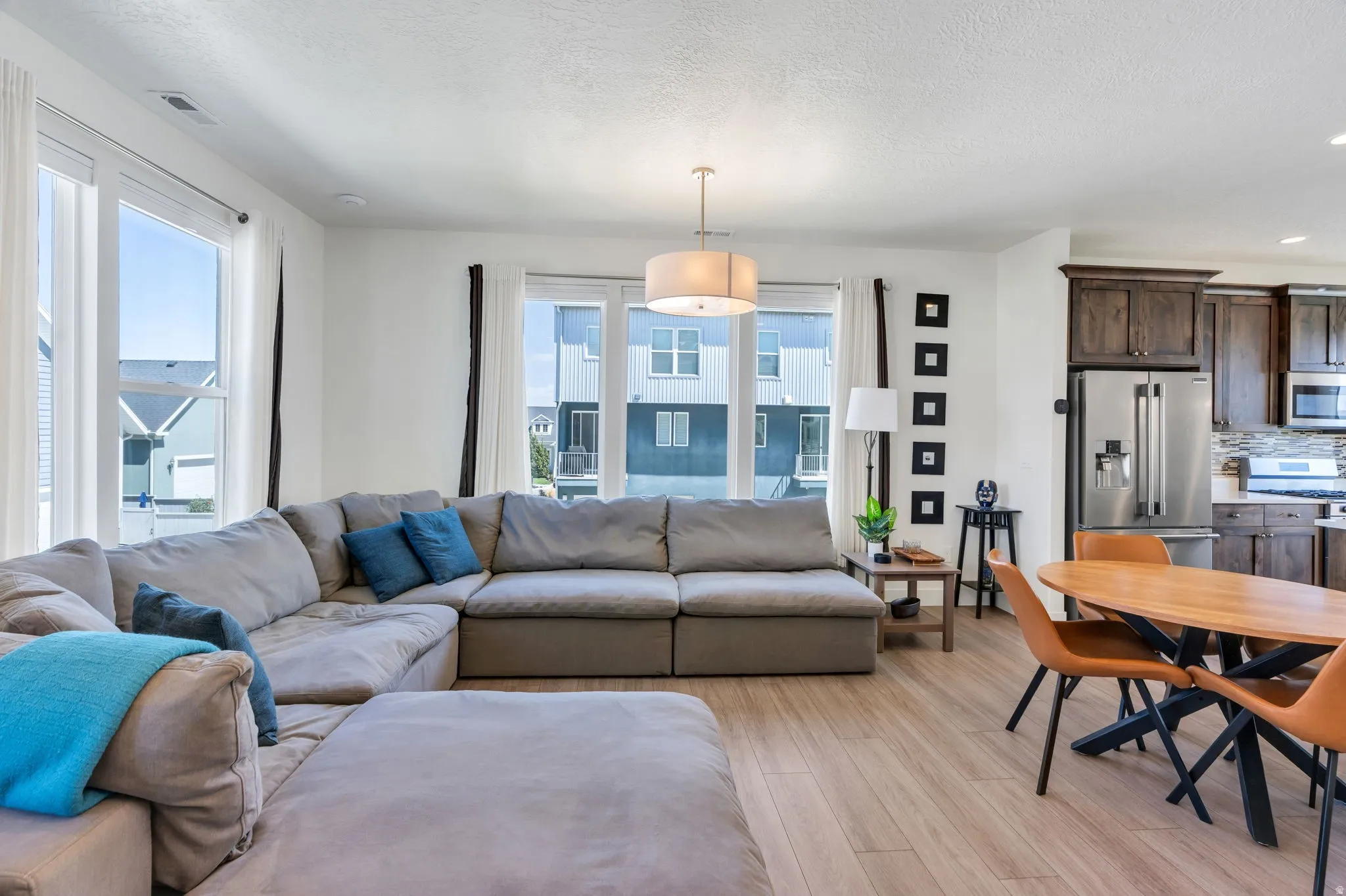 Open-concept living space featuring wood-finish flooring, recessed lighting, and large windows