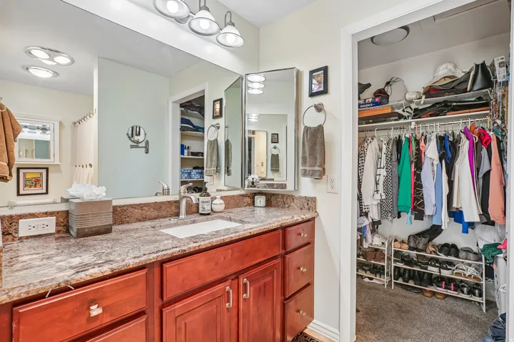 Vanity with a polished stone countertop, undermount sink, and chrome faucet