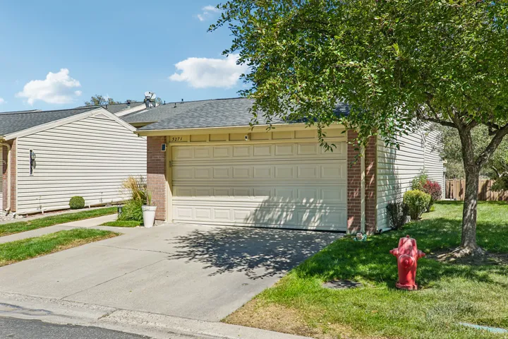 Attached garage with panel door, brick facade accents, and concrete driveway