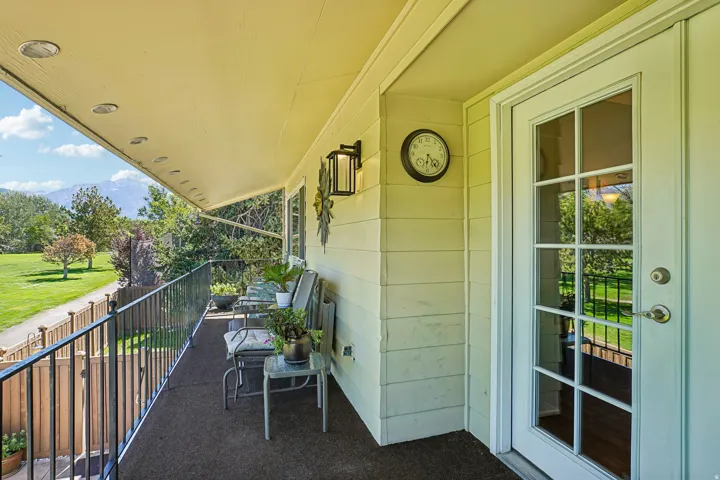 Covered balcony with recessed lighting, black metal railing, and exterior wall sconce