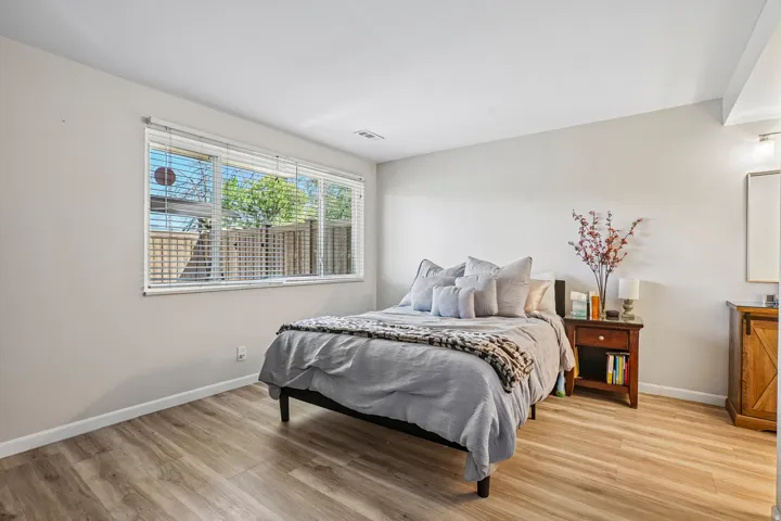 Expansive window with horizontal blinds, light wood-finish flooring, and light-toned wall paint