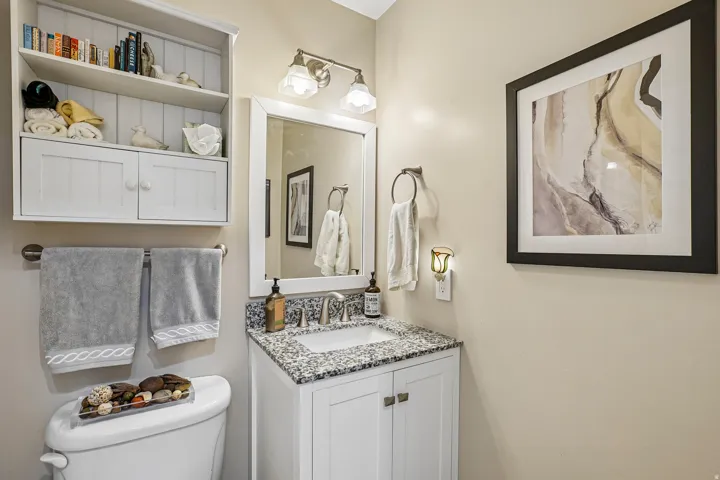 Vanity with an integrated sink, granite-patterned countertop, and white shaker-style cabinetry