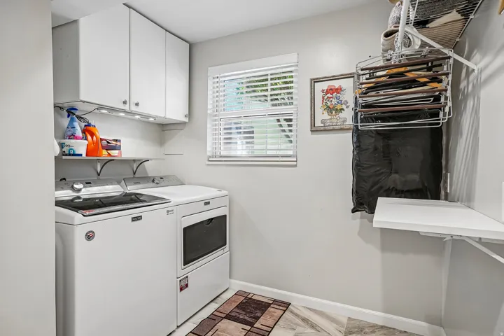 White cabinetry with under-cabinet lighting, a built-in shelf, and a window with blinds