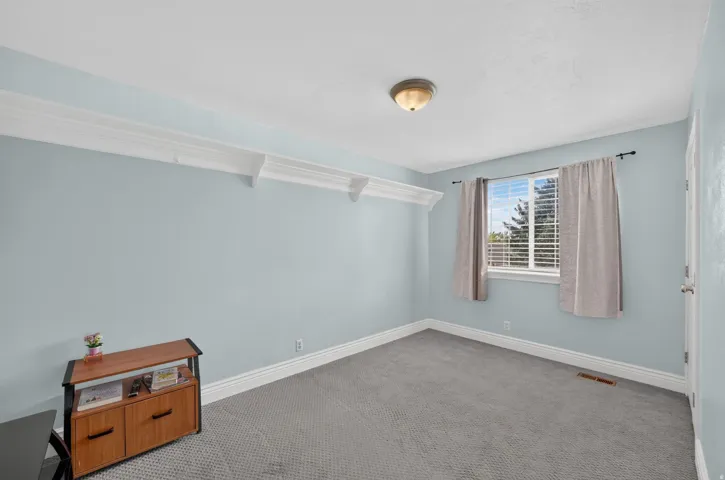 Recessed window with blinds, overhead flush mount light, crown molding, white trim, and gray patterned carpeting