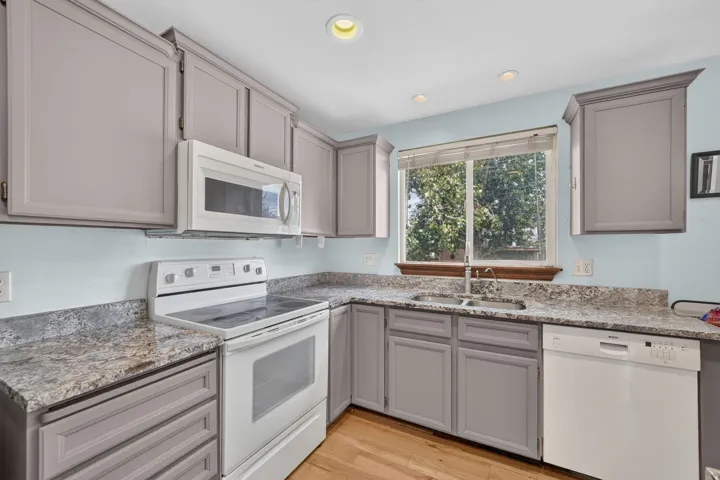 Kitchen featuring gray cabinetry, light-toned countertops, a stainless steel double sink, white appliances, and recessed lighting