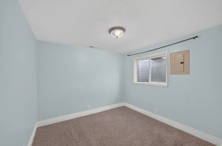 Recessed window with white trim, wall-mounted light fixture, and textured carpeting