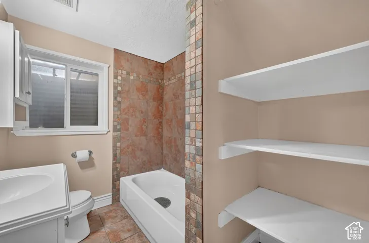 Built-in storage shelving, a tiled tub and shower combination, a single vanity with storage, and a window for natural light