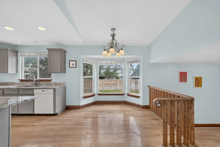 Kitchen and dining area featuring wood-finish flooring, a bay window, and a built-in kitchen sink with a gooseneck faucet