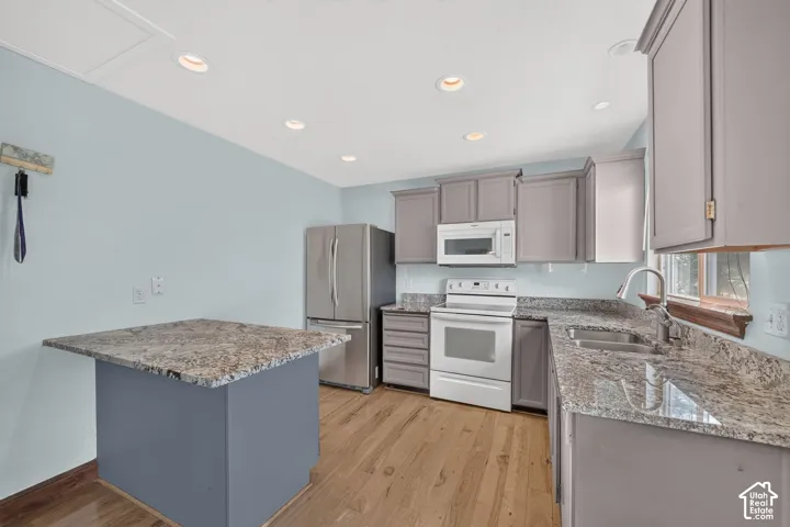 Kitchen featuring granite countertops, wood-finish flooring, recessed lighting, gray cabinetry, and stainless steel appliances