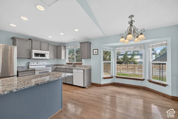 Kitchen featuring granite countertops, wood-finish flooring, recessed lighting, and a bay window with a decorative chandelier