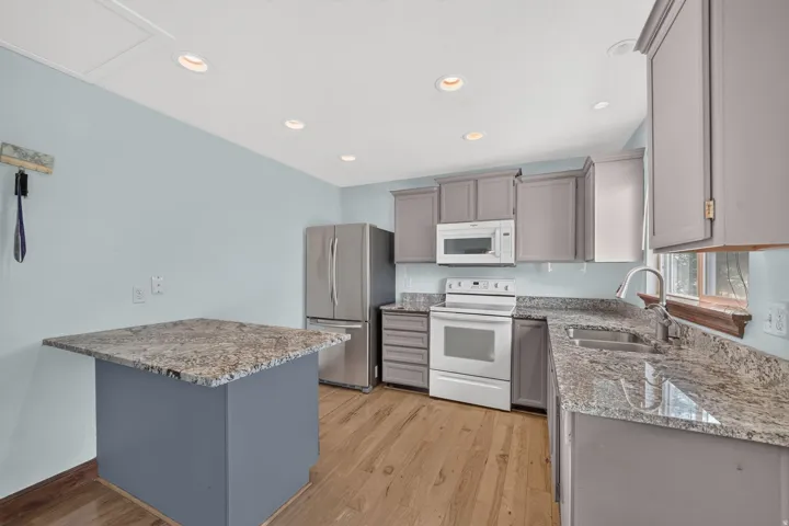 Kitchen featuring granite countertops, wood-finish flooring, recessed lighting, gray cabinetry, and stainless steel appliances