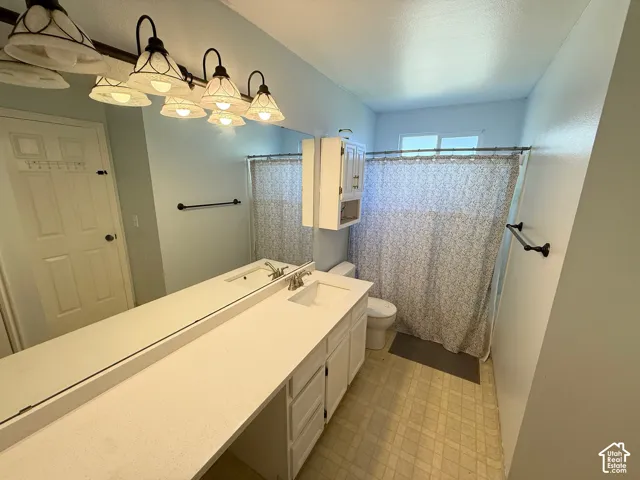 Bathroom featuring a dual-basin vanity with a solid-surface countertop, an expansive wall-to-wall mirror, multi-light fixture, built-in medicine cabinet, and a combination tub-shower with a fixed shower head