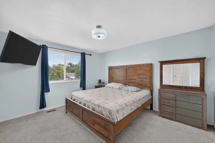 Plush carpeting, light blue wall paint, and a window with blinds