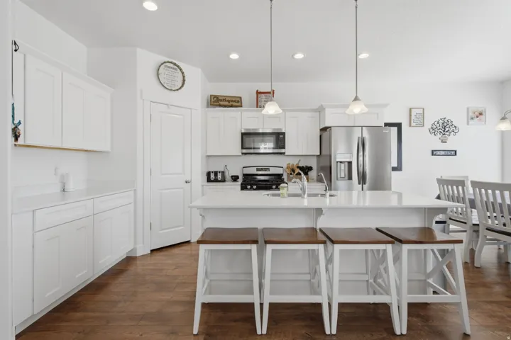 White shaker cabinetry, stainless steel appliances, recessed lighting, central island with seating