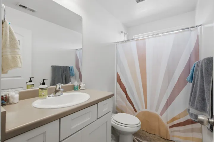 White vanity with shaker-style cabinetry, an integrated sink, and a chrome faucet