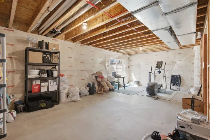 Unfinished basement with exposed ceiling joists, concrete flooring, and partial wall framing