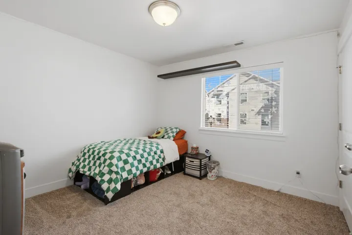 Carpeted room with a ceiling-mounted light fixture, a window with blinds, and a white paneled door