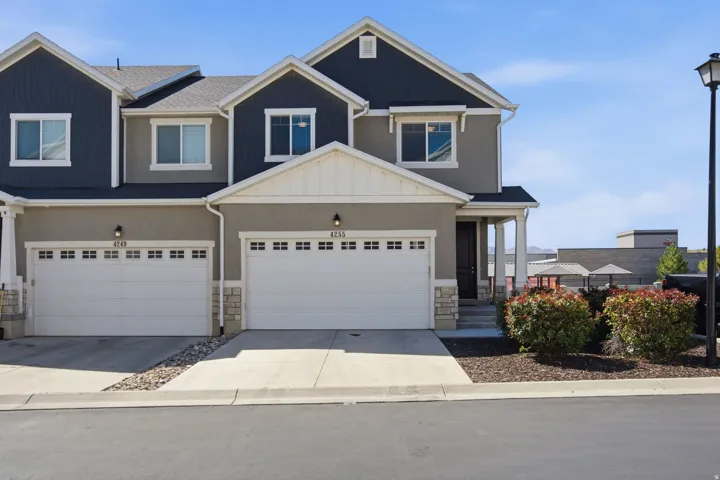 Contemporary townhome exterior featuring two garage bays, a covered entry, and a stone accent facade