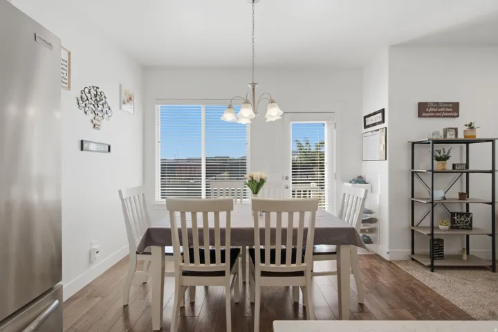 Wood-finish flooring, white walls, and a dining area with an overhead light fixture