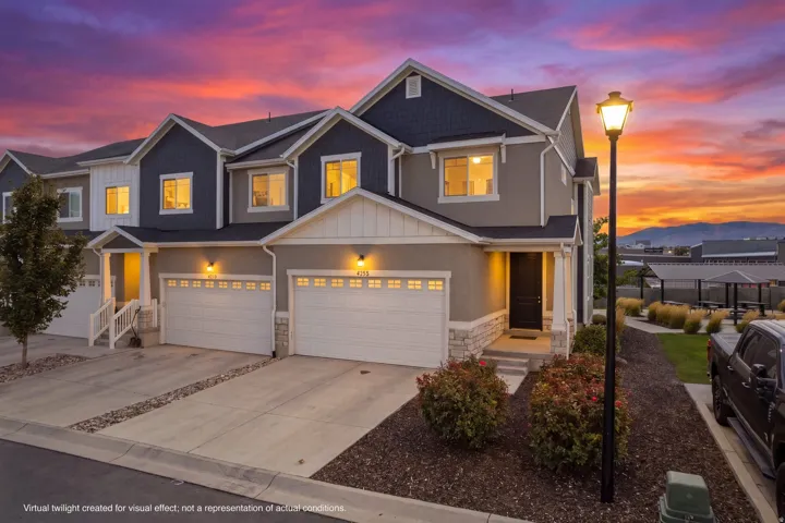 Multi-level townhome exterior with a two-car garage, covered entry, and landscaped front yard