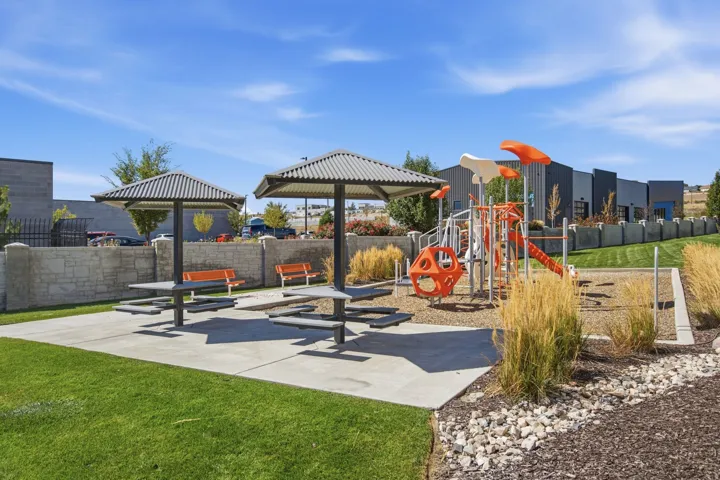 Just to the side and back of this townhome is the outdoor recreational area featuring a playground, picnic tables with shade structures, and built-in benches