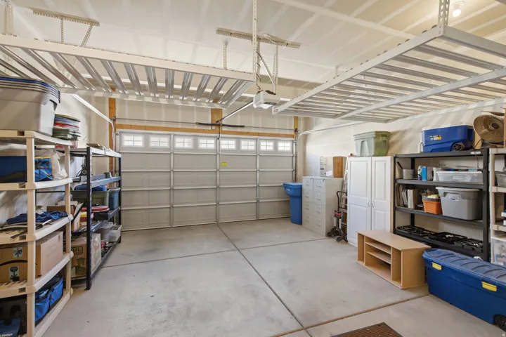 Garage with concrete flooring, overhead storage racks, an automatic garage door, and built-in white cabinetry